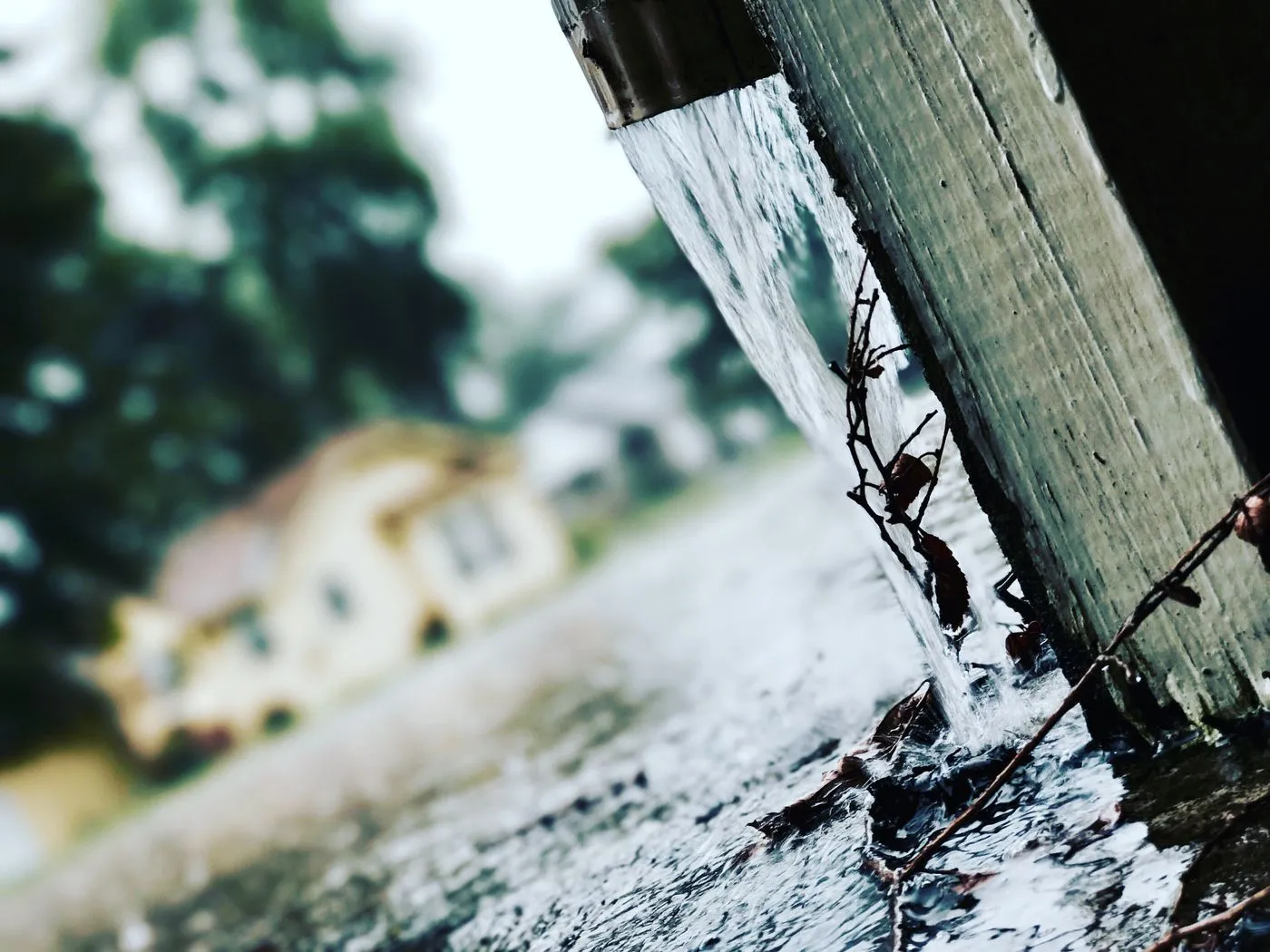 Rainwater running off a residential gutter and downspout during a storm