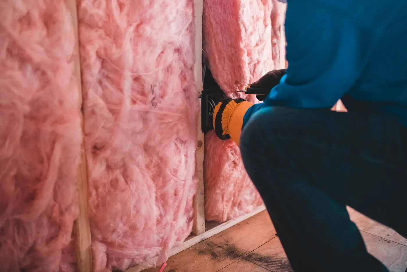 Installer fitting insulation batts between attic joists