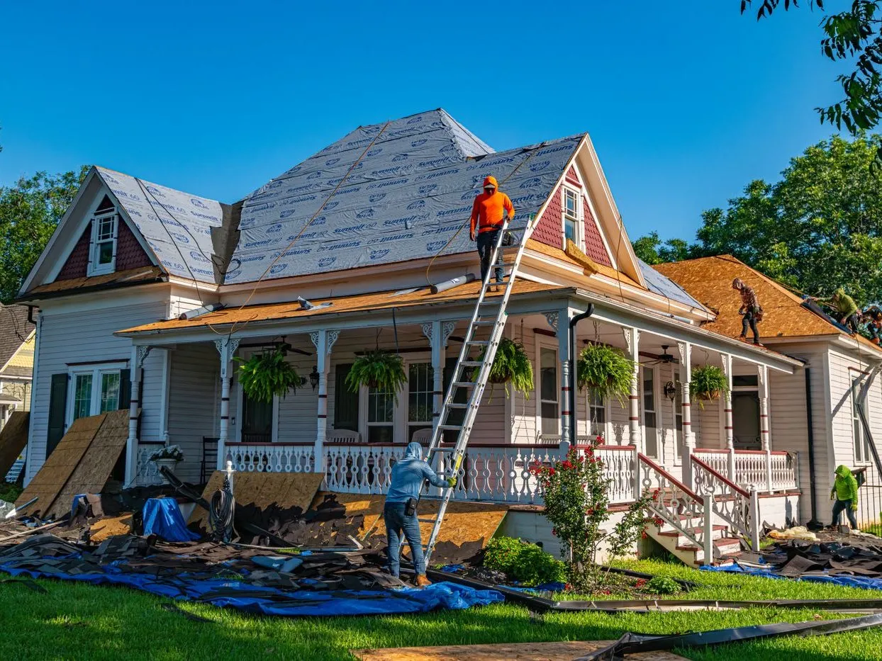 Roofing crew replacing shingles during a full roof replacement project